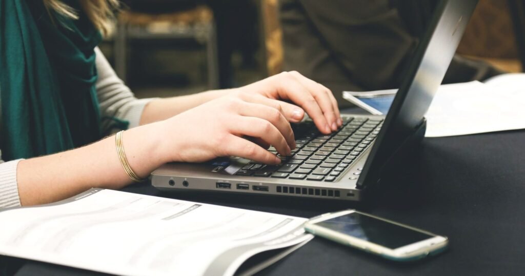 Small business owner downloading bank statements on a laptop and phone