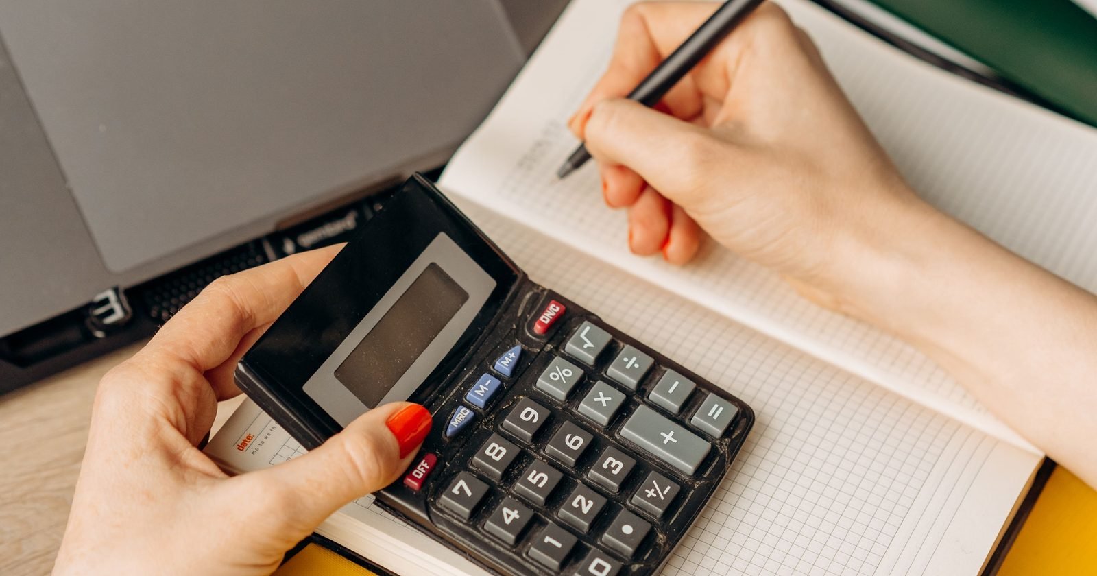 Sole trader preparing their annual accounts with a calculator and laptop